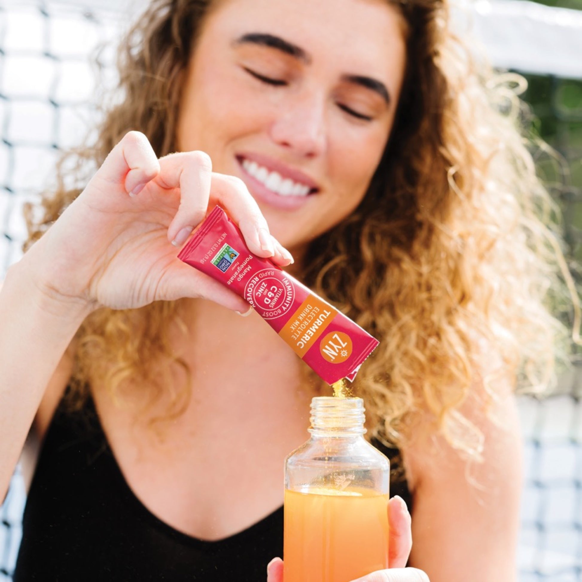 ZYN Mango Pomegranate Turmeric Electrolyte Drink Mix sachet being poured into a drink bottle